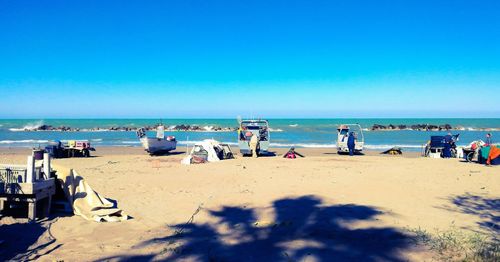 People on beach against clear blue sky