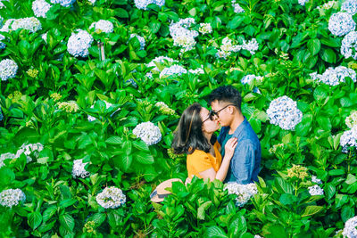 High angle view of couple kissing while standing amidst plants