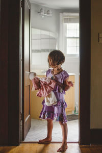 Full length of woman standing against door at home