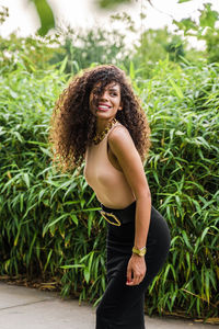 Portrait of young woman standing against plants