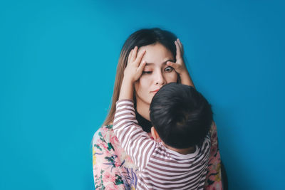 Close-up of mother and daughter against blue wall