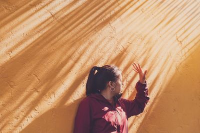 Woman gesturing standing against orange wall
