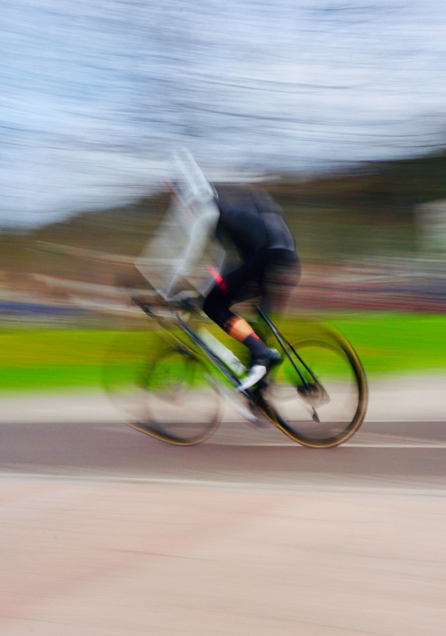 SIDE VIEW OF A MAN RIDING BICYCLE ON ROAD