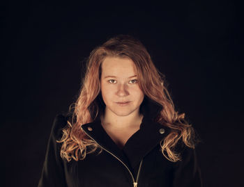 Portrait of beautiful young woman against black background