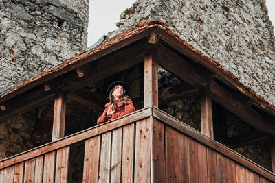 Young woman in winter clothes on wooden balcony of an old medieval castle.