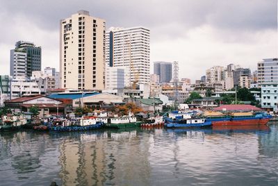 Boats moored at harbor against buildings in city