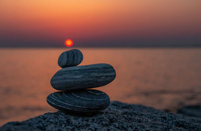 Balancing stones on rock against sea and sky during sunset