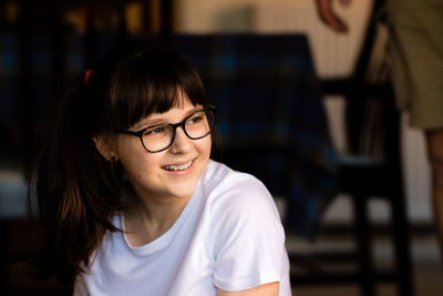 Smiling teenage girl wearing eyeglasses looking away
