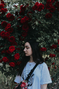 Beautiful woman standing by red flowering plants
