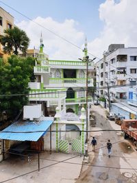 People by building in city against sky