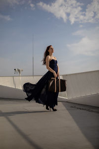 Young woman with bag standing on building terrace