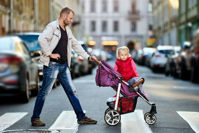 Full length of father with daughter in baby stroller