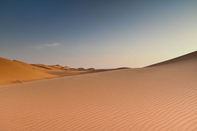 Sand dunes in desert against clear sky