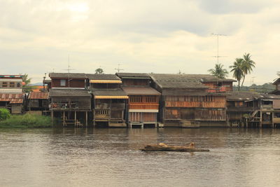 Houses by river against sky