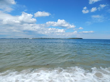 Scenic view of sea against cloudy sky on sunny day