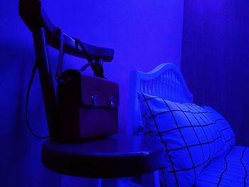 Illuminated electric lamp against blue wall at home