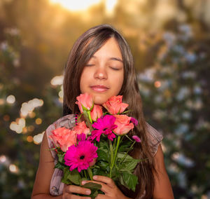 Portrait of smiling young woman holding flowers