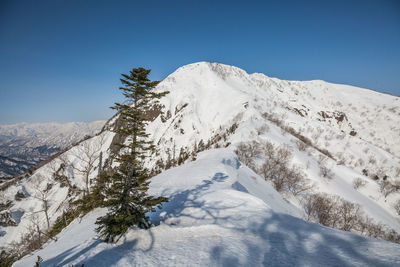 Scenic view of snowcapped mountains against clear blue sky