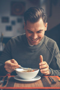 Portrait of man holding ice cream on table in restaurant