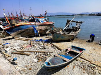 Fishing boats moored on sea shore against sky