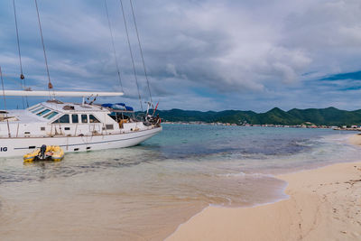 Sailboats moored on beach against sky