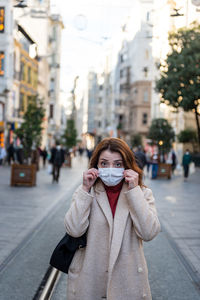 Portrait of woman wearing mask standing on city street