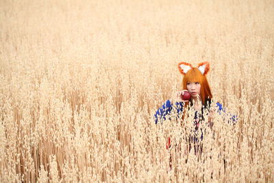 Woman wearing headband looking away while sitting amidst plants in farm