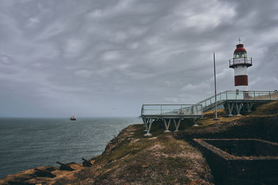 Lighthouse by sea against sky