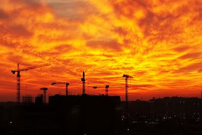 Silhouette of factory against orange sky