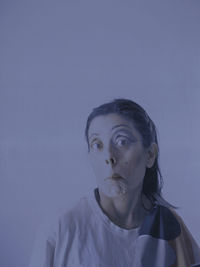 Portrait of mature woman making face against white background