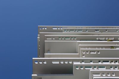 Low angle view of telephone booth against clear blue sky