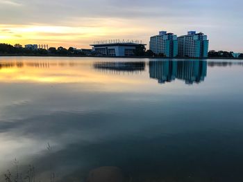 Reflection of buildings in lake against sky during sunset