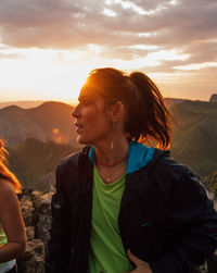 Beautiful woman and mountains against sky during sunset