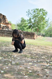 Full length of woman sitting on field against sky