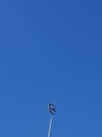 Low angle view of telephone pole against clear blue sky