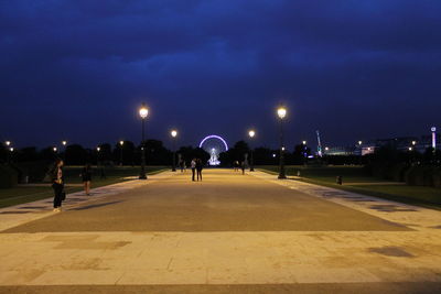 People walking on illuminated road at night