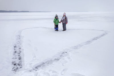 Rear view of people walking on snow covered land