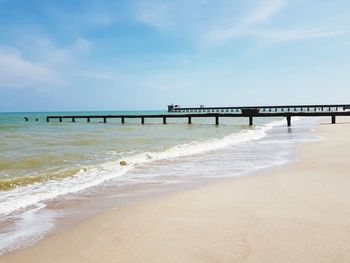 Pier on beach against sky