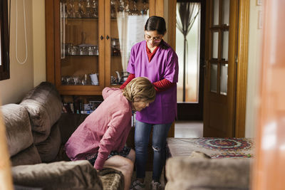 Smiling healthcare worker helping senior woman in living room at home