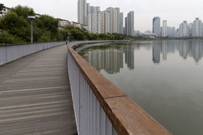 Bridge over river by buildings against sky in city