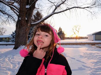 Portrait of girl showing finger on lips against snow during winter