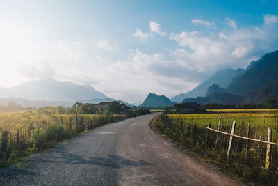Road amidst agricultural field against sky