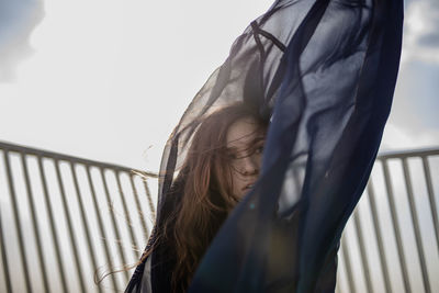 Beautiful young woman holding textile against railing