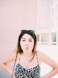 Portrait of a beautiful young woman standing against wall