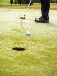 Golfer on golf course with dew, partial view