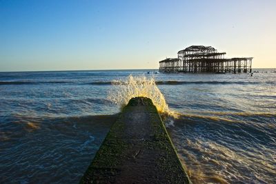 Wave splashing on jetty in sea against sky