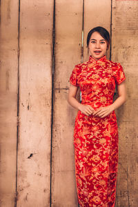 Portrait of a smiling young woman standing against wall