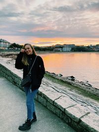 Portrait of young woman standing against sky during sunset