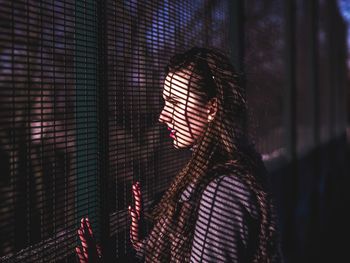 Side view of woman standing by fence at park