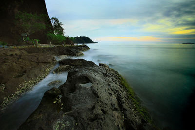 Scenic view of sea by cliff against sky